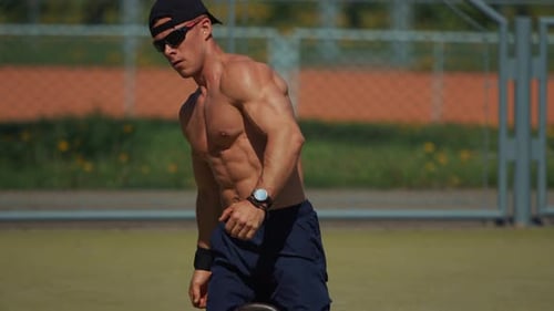 Young Shirtless Man After Strength Training with Kettlebell Shows Off His Big Biceps and Gives