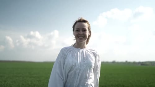 Beautiful girl walking on the green field. Girl at sunset on the wheat field