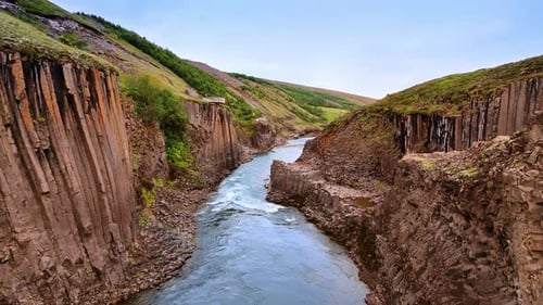 Des rochers colonnaires surplombent l'étroite rivière.
