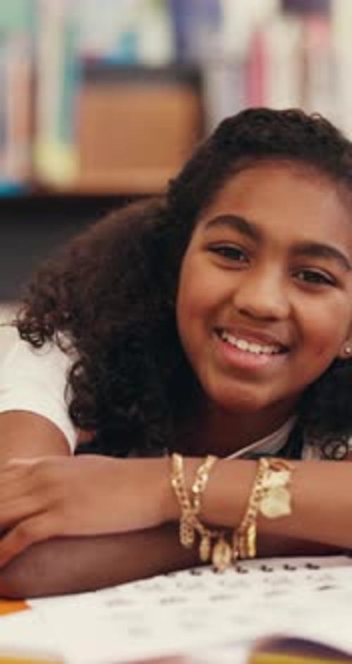 Smile, face and kid with study in library for exam preparation, homework assignment and learning