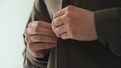Man Buttoning Up Brown Jacket Close Up