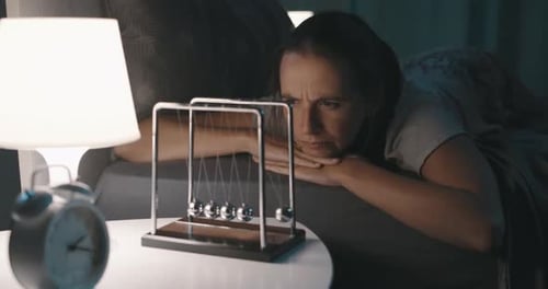 Woman Lying Awake at Night Watching Newton's Cradle