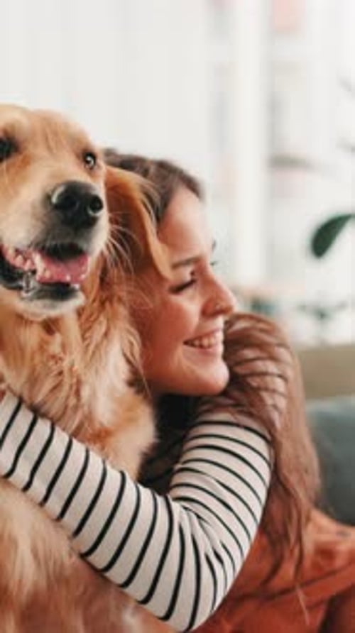 Happy Woman Hugging Golden Retriever Dog at Home