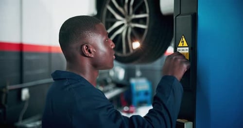 Garage, black man and mechanic with car lift for maintenance, vehicle inspection and service store
