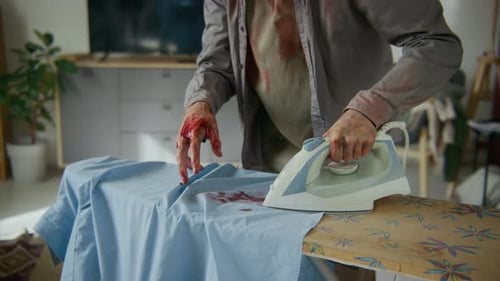 Undead Businessman Burning Hand with Hot Iron and Smearing Blood over Shirt
