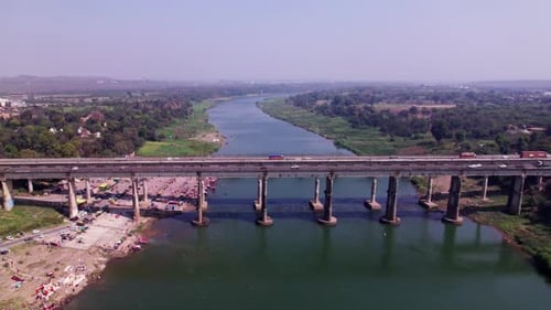 narmada river with greenery, haze and bridge at day time, push in, tilt down, drone shot, 4k.