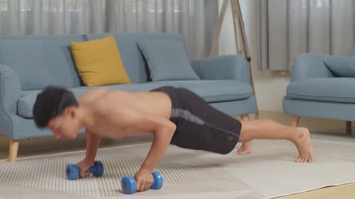 Asian Teenager Boy Doing Pushups With Dumbbells On Mat During The Shirtless Workout At Home