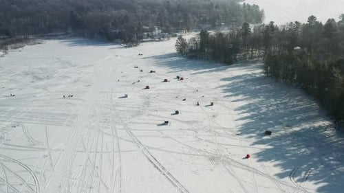 Aerial, ice fishing houses on a frozen lake during the winter day