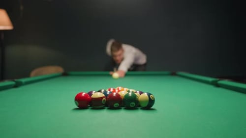 Verschwommener Billardspieler zielt bei gedämpftem Licht auf den grünen Billardtisch