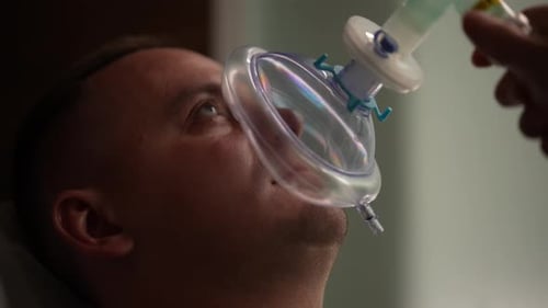 Gros plan des mains d'une femme médecin méconnaissable assistant un patient de sexe masculin subissant une respiration