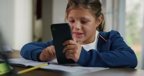 Smiling Girl Using Smartphone at Table Indoors