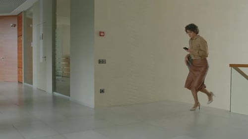 Businesswoman Going Towards Office Room Looking at Phone