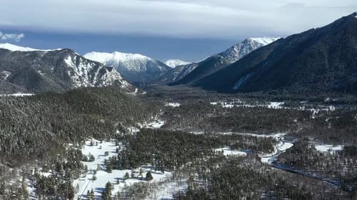 Air flight through mountain clouds over beautiful snow-capped peaks of mountains and glaciers.