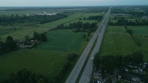 An Aerial Perspective Shows a Countryside with a Road Cutting Through Green Fields Filmed with a