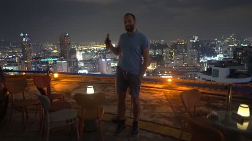 Portrait of Happy, Young Man Drinking Beer in Rooftop Bar at Night 30s