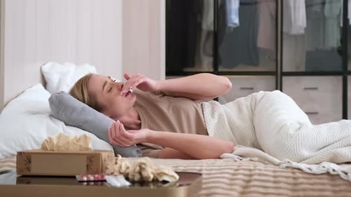 Une femme malade s'essuie le nez avec des serviettes alors qu'elle est allongée sur son lit à la maison