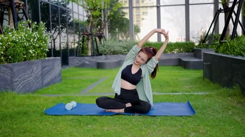 Woman Practicing Yoga on Lawn in Urban Setting
