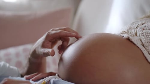 Gros plan de mains masculines doigtant le ventre d'une mère enceinte avancée Jeune couple attendant un bébé