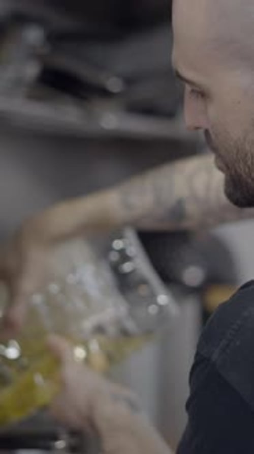 Seitenansicht eines männlichen Kochs, der in der Restaurantküche Speiseöl in einen Topf gießt