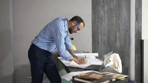 Architect working on blueprints in office
