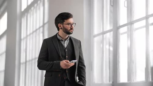 Portrait of Successful Businessman Using Modern Smartphone in Building with White Walls Medium Shot
