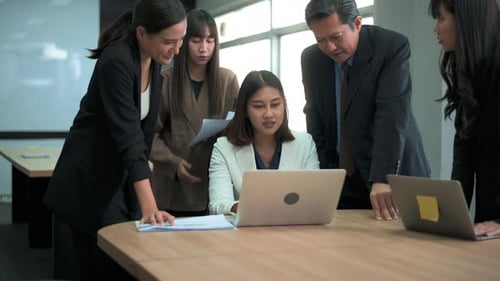 Group of business people looking at computer and discussing in modern office