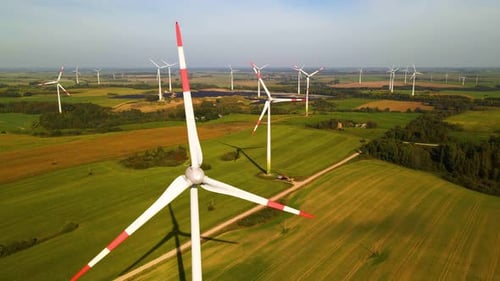 Aerial footage of wind turbines in a wind farm generating green electric energy on a wide green fiel