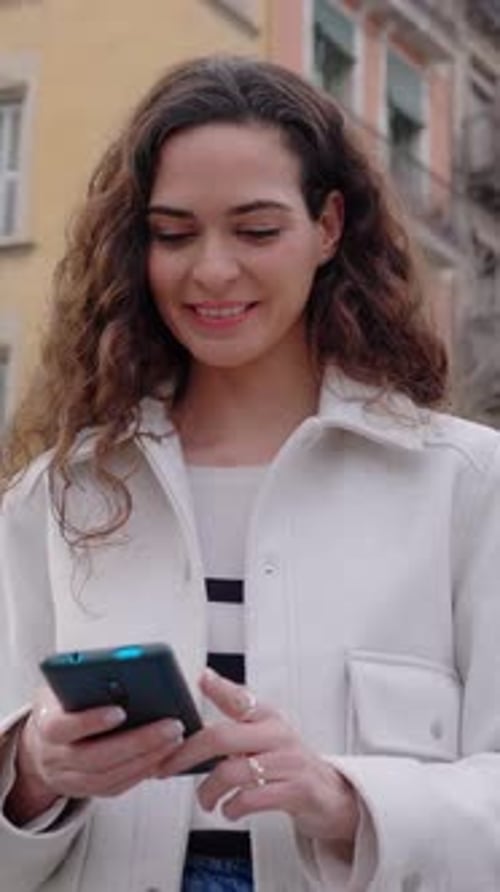 Beautiful Young Woman Using Mobile Phone Standing at City Street