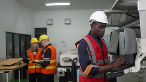Blue-Collar Worker Analyzes Data on Laptop at Manufacturing Facility