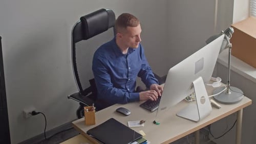 Two Focused Office Employees Typing on Computers while Working in Office