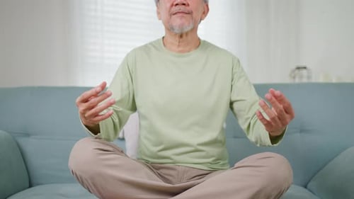 Senior Man Meditating on Couch at Home