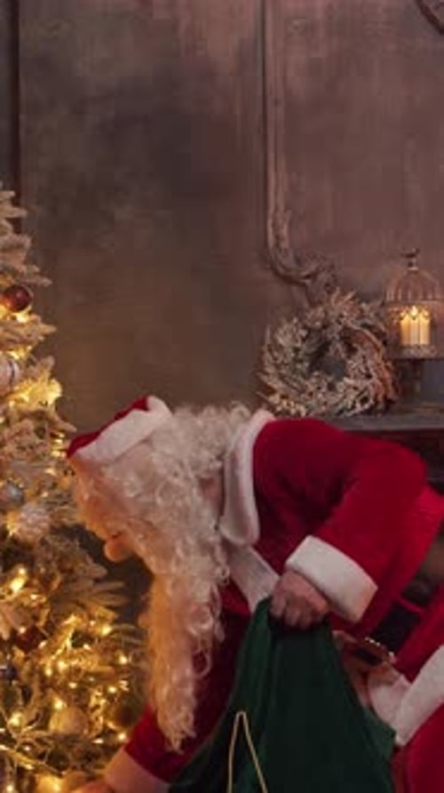 Santa Claus's Workshop Santa is Busy Wrapping a Gift at the Table with a Fireplace and Christmas