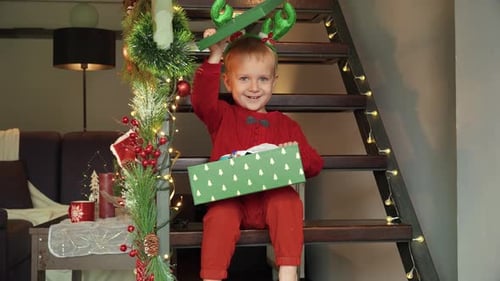 Excited Child Opening Christmas Present on Stairs