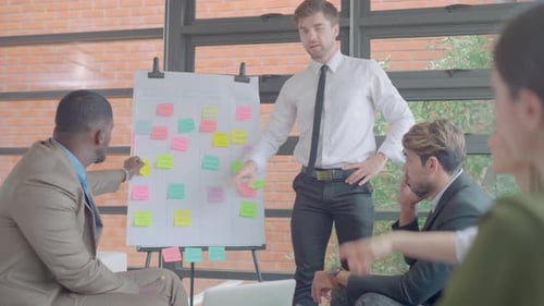 Caucasian manager man stand and present work on board and discuss with his team in meeting area