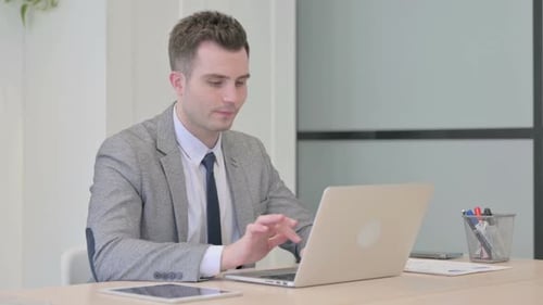 Young Businessman Leaving Office after Closing Laptop in Evening