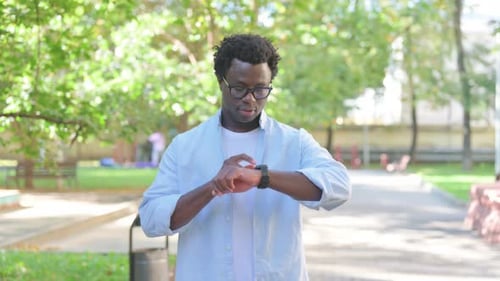 Man in Park Interacts with Smartwatch Technology