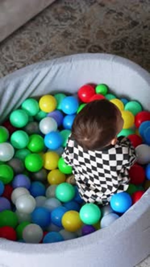 Baby boy in black and white pajama sits in the dry pool.
