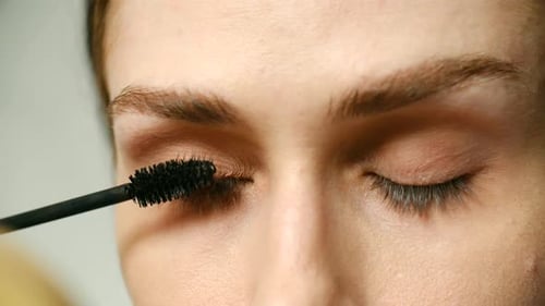 Woman Applying Mascara to Eyelashes in Close Up
