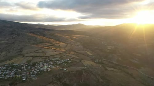 Vue aérienne des terres agricoles fertiles et du village sur le versant de la montagne au lever du soleil