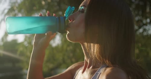Closeup of athletic woman drink water after workout outdoors