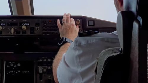 Pilot in the cockpit adjusting controls, flying plane