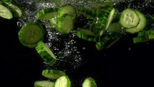 Super Slow Motion of Falling Fresh Cucumber Slices in Water