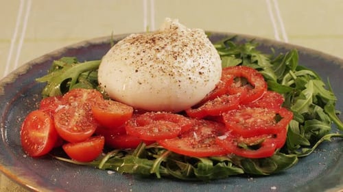 Burrata or Mozzarella Cheese on Fresh Tomatoes and Green Arugula on Plate Closeup From Italian Cow's