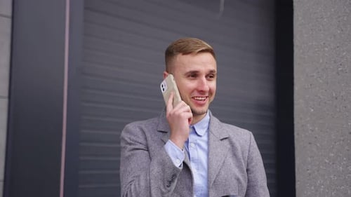 Man in Blazer Talking on Phone With Coffee