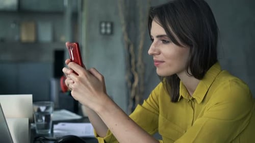 Young Happy Businesswoman Texting on Smartphone Sitting by Table at Home Office Adult