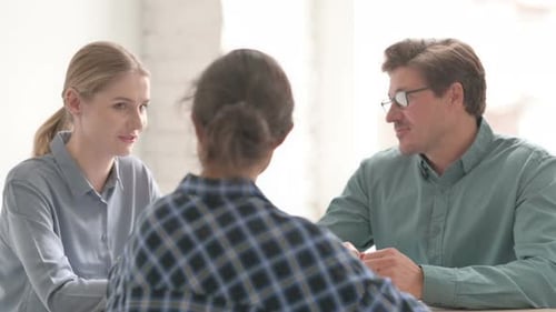 Three People Engaging in Workplace Meeting