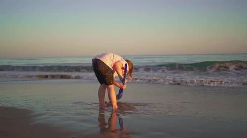 Child Digging with Shovel on Sandy Beach at Sunset