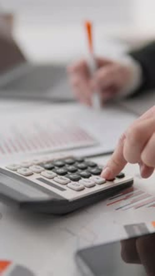 Dans l'image, un homme d'affaires se concentre sur la planification financière à l'aide d'une calculatrice mettant en évidence