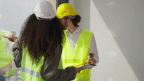 Engineers Discussing Plans On Tablet At Construction Site