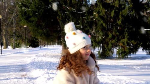 Glückliches kleines Mädchen, das Schnee wirft